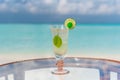 Tasty icy tropical cocktail with lime on the glass table at the beach with ocean Royalty Free Stock Photo