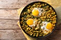 Tasty Iranian dish stew of beans and dill with fried eggs, garlic, turmeric close-up on a table. horizontal top view