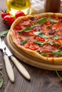 Tasty italian pizza with ham, cheese, tomatoes on cutting board with cutlery. Royalty Free Stock Photo