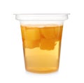 Tasty jelly dessert with slices of fruit in plastic cup on white