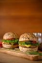 Tasty juicy beef burgers on wooden tray. Beef burger with cheese, lettuce, tomato slides