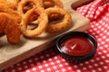Tasty ketchup with chicken nuggets and onion rings on checkered cloth, closeup Royalty Free Stock Photo