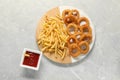 Tasty ketchup with fries and onion rings on grey marble table, flat lay Royalty Free Stock Photo