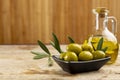 Tasty looking olives extra virgin olive oil and olive leafs on wooden background