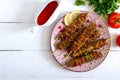 Tasty lula kebab on the plate on a white wooden table. Chopped meat on wooden skewers, grilled. Eastern cuisine. Royalty Free Stock Photo