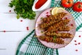 Tasty lula kebab on the plate on a white wooden table. Chopped meat on wooden skewers, grilled. Eastern cuisine. Royalty Free Stock Photo