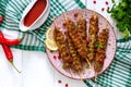 Tasty lula kebab on the plate on a white wooden table. Chopped meat on wooden skewers, grilled. Eastern cuisine. Royalty Free Stock Photo