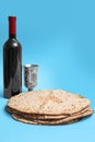 Tasty matzos, wine and goblet on light blue background, space for text. Passover Pesach celebration Royalty Free Stock Photo