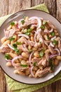 Tasty Mediterranean style tuna salad with white beans and onions close-up in a plate. Vertical top view
