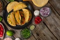 Tasty mexican tacos on the black round plate on the wooden background. Tomatoes, oil, spices, lime are on the table. Traditional Royalty Free Stock Photo
