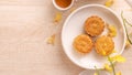 Tasty moon cake for Mid-Autumn festival on bright wooden table, concept of festive afternoon tea decorated with yellow flowers,