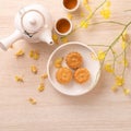 Tasty moon cake for Mid-Autumn festival on bright wooden table, concept of festive afternoon tea decorated with yellow flowers,