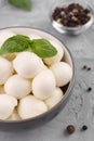 Tasty mozzarella balls and basil leaves in bowl on grey table, above view Royalty Free Stock Photo