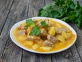 Romanian cuisine - fresh homemade meat and potatoes with parsley. Stew with pork and vegetables on a wooden background