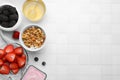 Tasty oatmeal, fresh berries, yogurt and honey on white tiled table, flat lay with space for text. Healthy breakfast Royalty Free Stock Photo