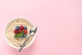 Tasty oatmeal porridge with raspberries, blueberries and spoon in bowl on pink background, top view Royalty Free Stock Photo