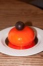 tasty orange cake with chocolate ball on white plate on wooden table