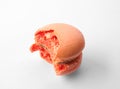 Tasty orange macaron with bite mark on white background