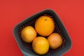 Tasty oranges in a vase on a red background