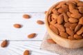 Tasty organic peeled almond snack in wooden bowl on white wooden background with copy space.Close up heap almonds shelled nut .