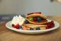Tasty pancakes with fresh berries and whipped cream on wooden table Royalty Free Stock Photo