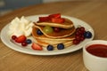 Tasty pancakes with fresh berries and whipped cream on wooden table Royalty Free Stock Photo