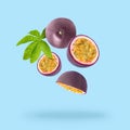 Tasty passion fruits and passiflora leaf falling on light blue background