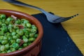 Tasty Peas with ham in a clay bowl decorated with an fork on a black slate board