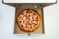 Tasty pepperoni pizza inside open box, white background. Pizza in cardboard box