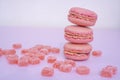 Tasty pink raspberry macarons on light violet background. French homemade dessert with small broken pieces