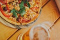 Tasty pizza and glass of beer are on wooden table Royalty Free Stock Photo