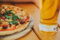 Tasty pizza and glass of beer are on wooden table Royalty Free Stock Photo