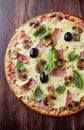 Tasty pizza with ham, champignon mushrooms, mozzarella cheese, black olives and fresh basil on wooden background Royalty Free Stock Photo