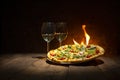 A tasty pizza just from the stove and two wine glasses standing on the wooden rustic table against the fire