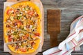 Tasty pizza with mushrooms, chicken, pepperoni, olives, corn cut into pieces on a wooden tray. Royalty Free Stock Photo