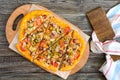 Tasty pizza with mushrooms, chicken, pepperoni, olives, corn cut into pieces on a wooden tray. Royalty Free Stock Photo