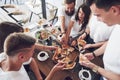 Tasty pizza on the table, with a group of young smiling people resting in the pub Royalty Free Stock Photo