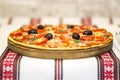 Tasty pizza with vegetables, basil, olives, tomatoes, green pepper on cutting board, table cloth traditional colorful Royalty Free Stock Photo