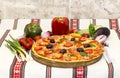 Tasty pizza with vegetables, basil, olives, tomatoes, green pepper on cutting board, table cloth traditional colorful Royalty Free Stock Photo