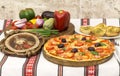 Tasty pizza with vegetables, basil, olives, tomatoes, green pepper on cutting board, table cloth traditional colorful Royalty Free Stock Photo