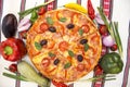 Tasty pizza with vegetables, basil, olives, tomatoes, green pepper on cutting board, table cloth traditional colorful Royalty Free Stock Photo