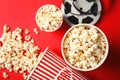 Tasty popcorn and film reel on color background, top view.