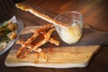 Tasty pork crackling strips and an apple sauce dip in a glass on a wooden board served as a snack or appetiser