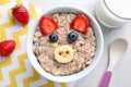 Tasty porridge served with berries and milk on marble table. Creative idea for kids breakfast