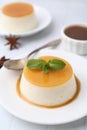 Tasty pudding with caramel sauce served on white tiled table, closeup Royalty Free Stock Photo