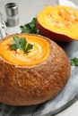 Tasty pumpkin cream soup in bread loaf on table