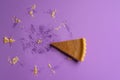 Tasty pumpkin pie slice and the visible traces of a whole pie, on a purple background. Minimalism image. Delicious holiday dessert