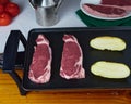 Tasty Raw Beefsteak with raw caliu potatoes on a electric griddle