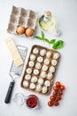 Tasty raw tortellini with flour and basil in wooden tray  on white background   top view flat lay Royalty Free Stock Photo