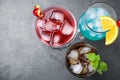 Tasty refreshing cocktails in glasses on grey stone table, flat lay.